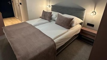 A double bed with a headboard, bedside tables, and a wall-mounted light fixture.
