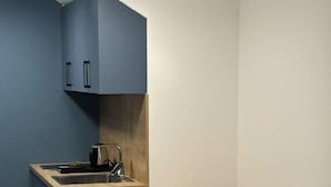 A compact kitchen with a wooden table and two chairs, a sink, and cabinets. - Alinar Oasis Budget Hotel (Sarajevo)