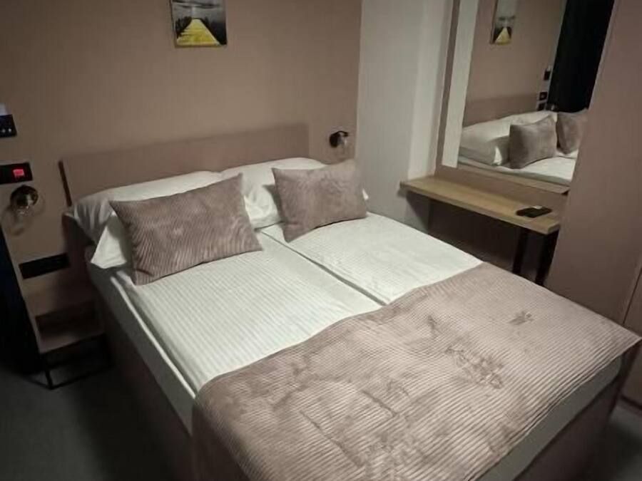 A single bed with a headboard, a bedside table, and a mirror.