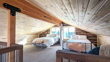 Un dormitorio acogedor en el ático con dos camas, techo de madera y vistas al exterior.
