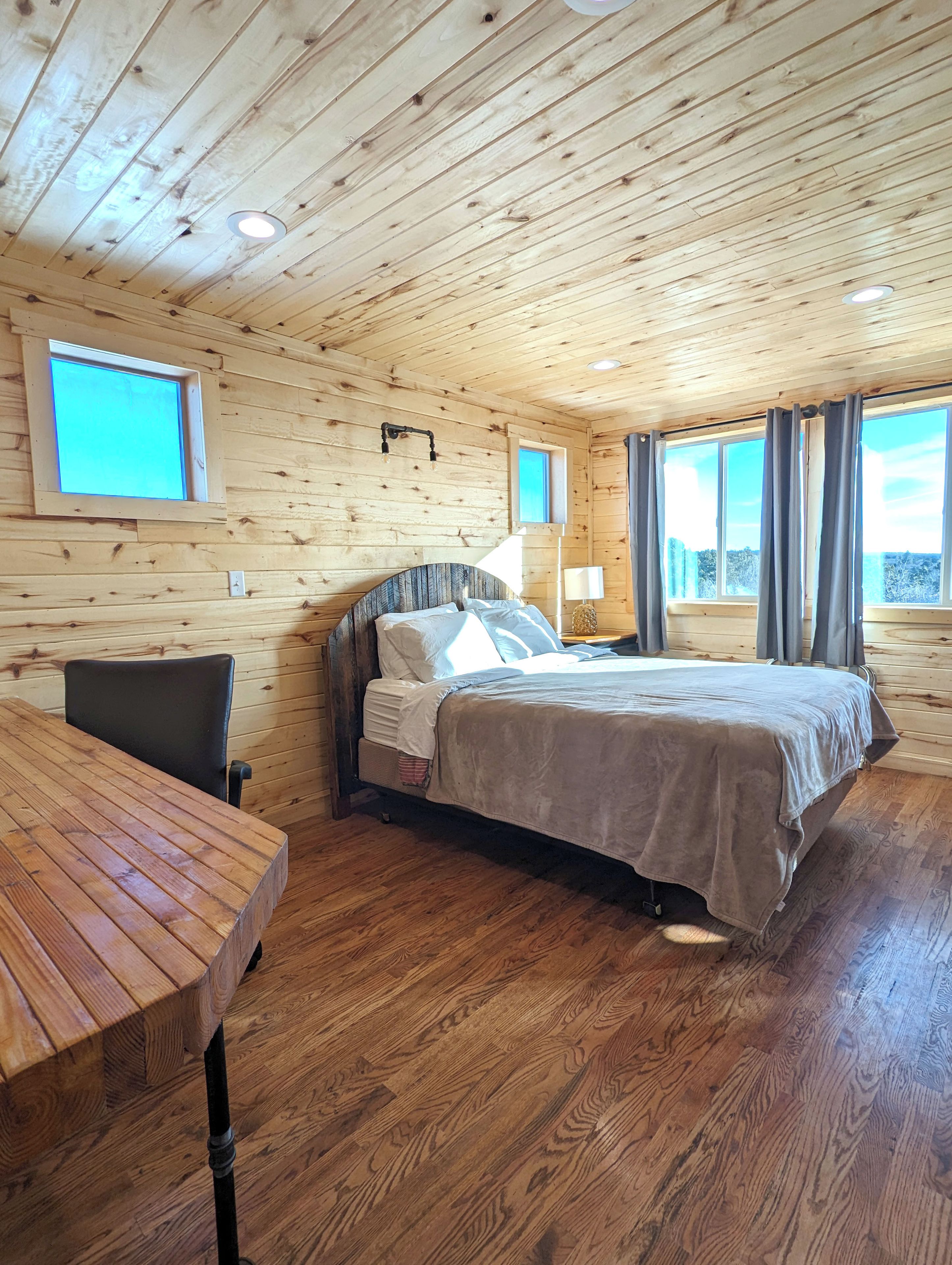 Une chambre dans une cabane en bois, avec un lit, une table et une fenêtre.