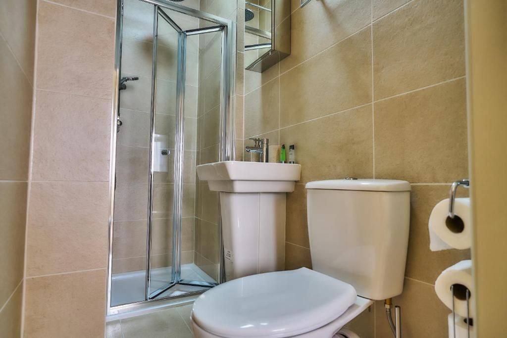 A bathroom with a glass shower enclosure, a white toilet, and a sink.