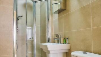 A bathroom with a glass-enclosed shower, a white sink, and a toilet.
