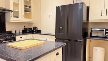 Una cocina con un refrigerador negro, un tostador y una cafetera.