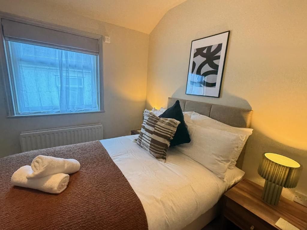 A hotel room with a bed, a window, a wall-mounted artwork, and a bedside lamp.