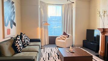 A modern living room with a sofa, a coffee table, a lamp, and a television.