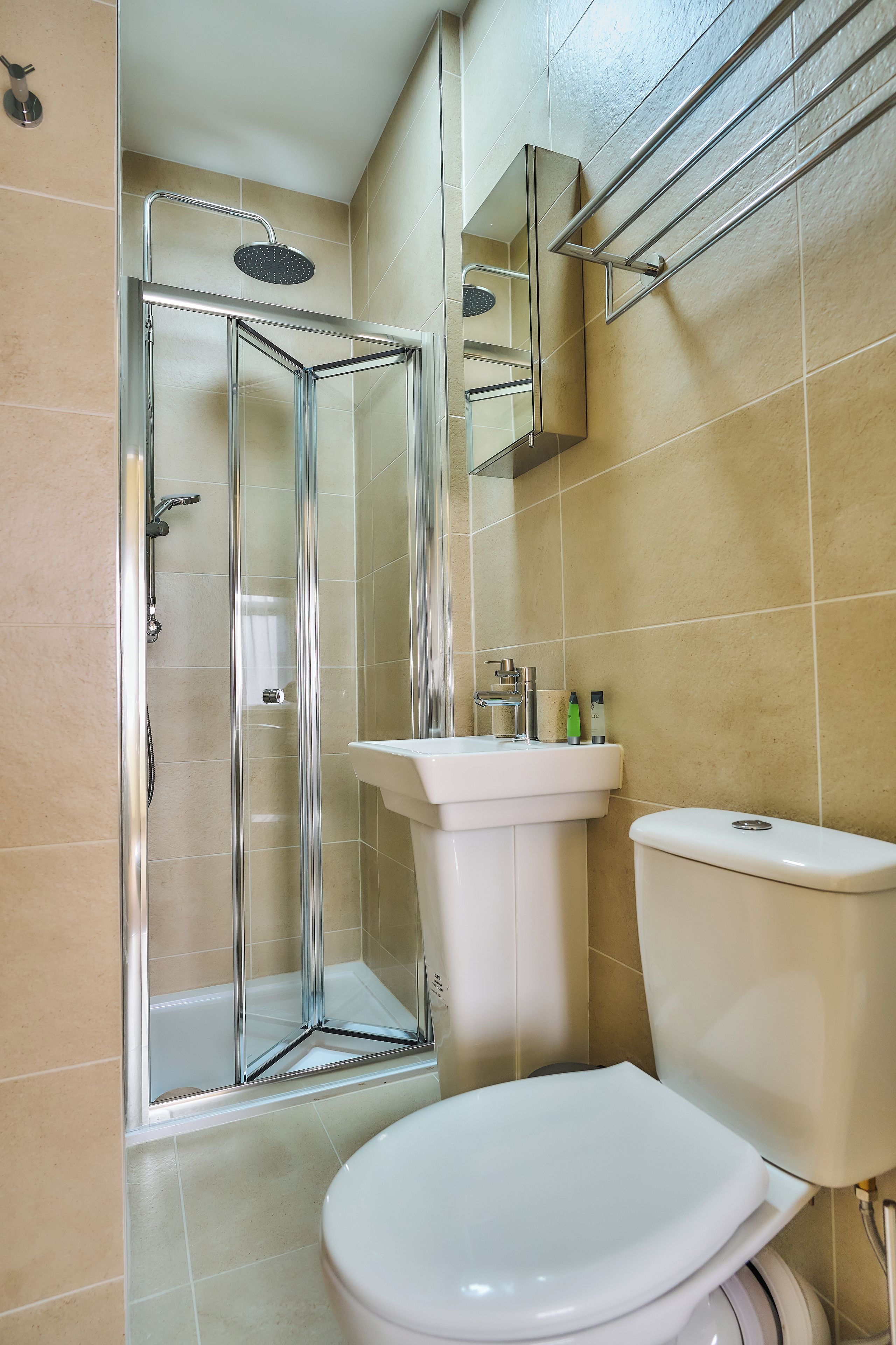 A bathroom with a glass-enclosed shower, a white sink, and a toilet.