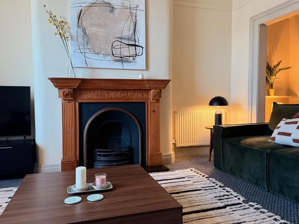 A living room with a fireplace, a television, a coffee table with candles, and a sofa.