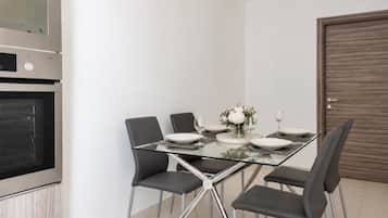 A modern dining area with a glass table, six chairs, and a wooden door.