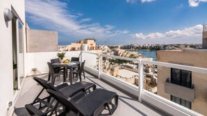 A balcony with a table and chairs, overlooking a cityscape and a body of water. - Sea Views & Terrace - 2BR Penthouse, St Julian's (San Ġiljan)