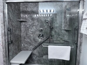 Une cabine de douche moderne avec une porte en verre et une douchette à main.