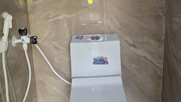 Une salle de bain avec des toilettes, une douche et une fenêtre.