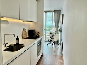 A modern kitchen with a built-in oven, a coffee machine, and a sink. - Skyline Rotunda Studio Apartment (Birmingham)