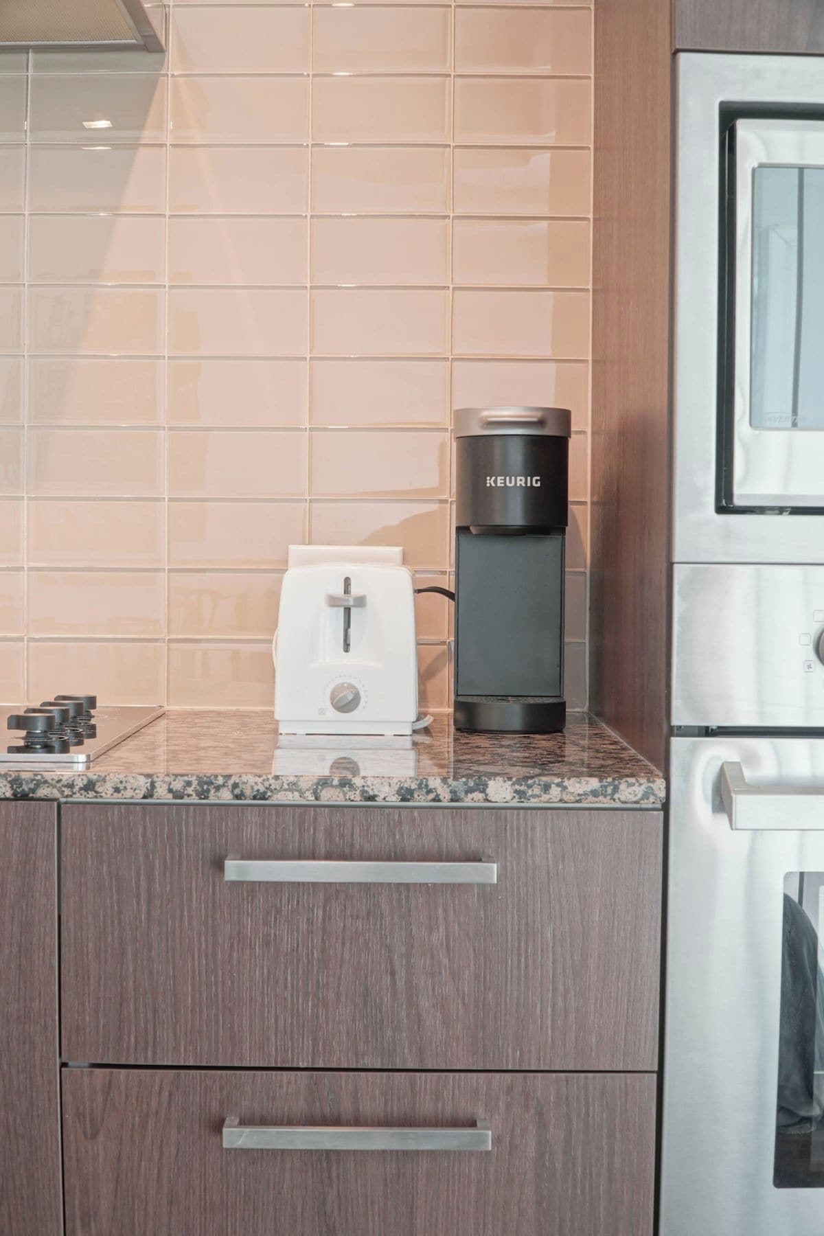 A kitchen with a coffee maker, toaster, and a microwave on a granite countertop.