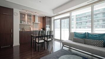 A modern apartment with a dining area, kitchenette, and a sofa with patterned cushions.