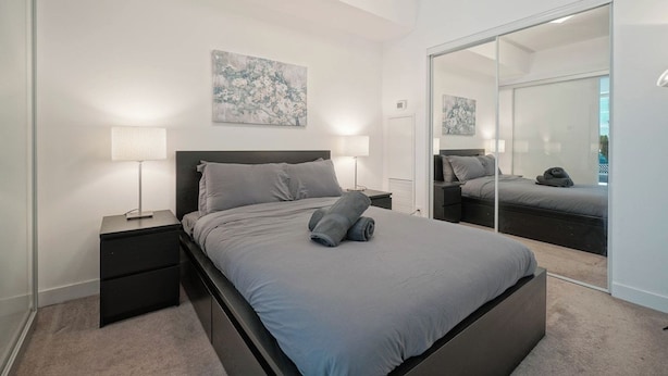 A bedroom with a bed, nightstands, a mirror, and artwork on the wall. - Bright 1Bedroom w/ Balcony Steps to CN Tower-MTCC (Toronto)