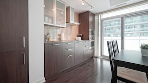 A modern kitchen with dark wood cabinets, stainless steel appliances, and a large window providing natural light. - Bright 1Bedroom w/ Balcony Steps to CN Tower-MTCC (Toronto)
