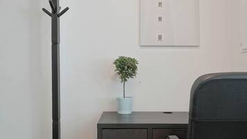 A modern office space with a desk, chair, coat stand, and a framed picture on the wall.