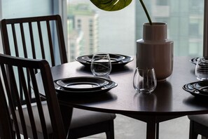 A dining table set with plates, glasses, and a vase with a plant. - Charming 1BR Downtown Condo with Lakeview Balcony (Toronto)