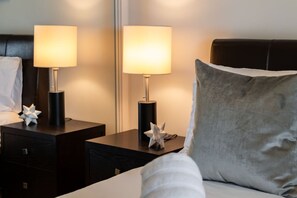 A hotel room with a bed, two bedside tables with lamps, a mirror, and a decorative star ornament on each table. - Charming 1BR Downtown Condo with Lakeview Balcony (Toronto)