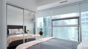 A modern bedroom with a large bed, a glass partition, and a city view. - Prime Oasis- Free Parking, Sleeps 5,CN Tower, MTCC (Toronto)