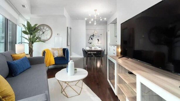A modern living room with a sofa, coffee table, and a large flat-screen TV. - Prime Oasis- Free Parking, Sleeps 5,CN Tower, MTCC (Toronto)