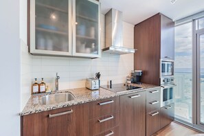 A modern kitchen with granite countertops, stainless steel appliances, and wooden cabinets. - Cozy Toronto Condo with CN Tower View & Workspace (Toronto)