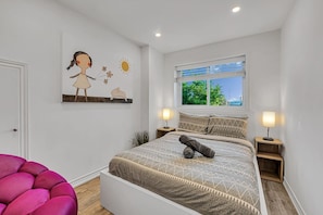 A bedroom with a bed, two bedside tables, a window with a view, and a wall with a painting. - 5BR North York Home - Sleeps 11 - Parking (Toronto)