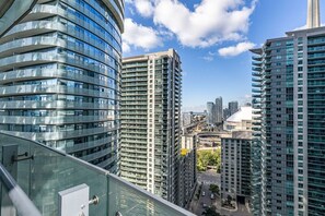 A high-rise building with a curved glass facade, surrounded by other tall buildings. - 2BR Condo w/ Stunning CN Tower View & Free Parking (Toronto)