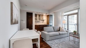A modern apartment with a dining area, sofa, and kitchenette. - 2BR Condo w/ Stunning CN Tower View & Free Parking (Toronto)
