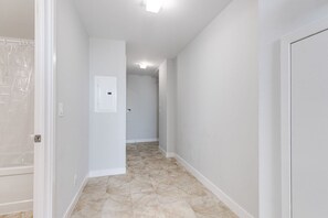 A hallway with a tiled floor, white walls, and a door at the end. - 2BR Condo w/ Stunning CN Tower View & Free Parking (Toronto)