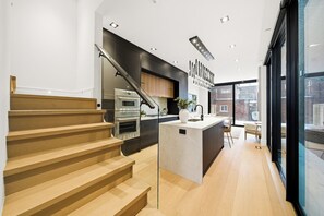 A modern kitchen with a central island, a staircase, and a view of the outside. - Luxury Toronto Home with Rooftop Terrace & Parking (Toronto)