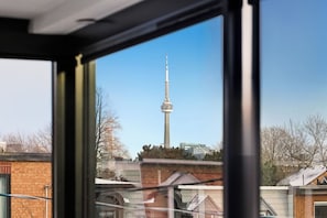 A view of a tall tower from a window, with buildings and trees in the foreground. - Luxury Toronto Home with Rooftop Terrace & Parking (Toronto)