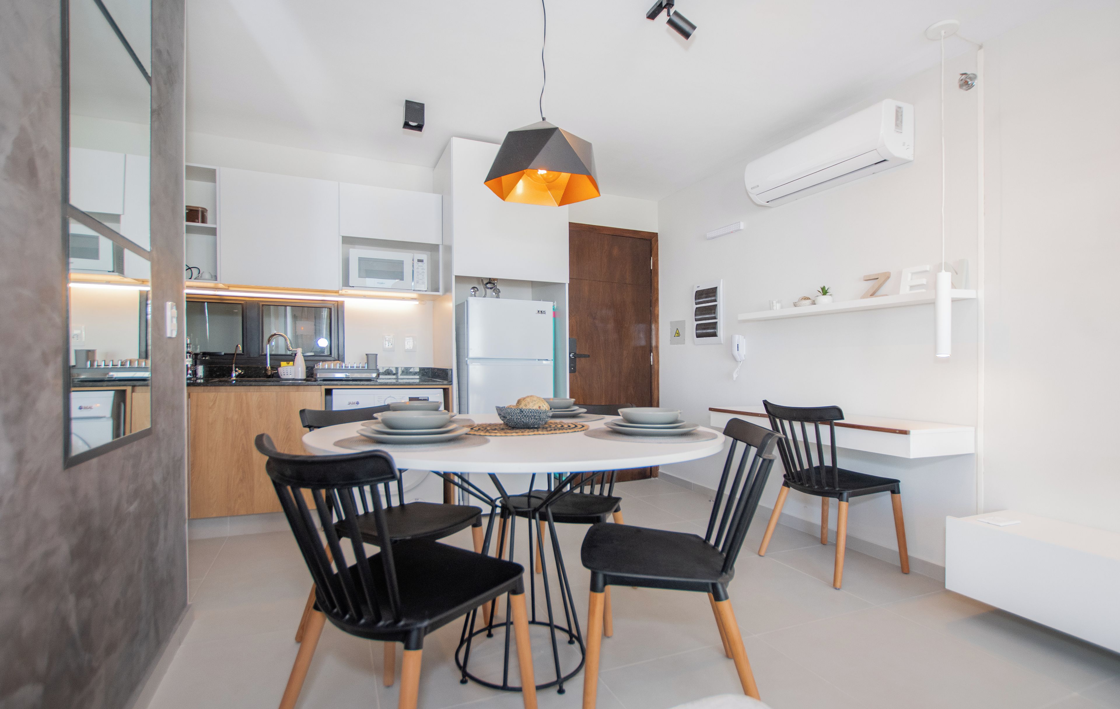 Una cocina moderna con armarios blancos, una isla central y sillas negras alrededor de una mesa redonda.