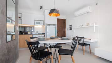 Una cocina moderna con armarios blancos, una isla central y sillas negras alrededor de una mesa redonda.