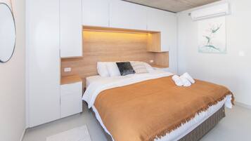 A modern bedroom with a bed, bedside tables, and an air conditioning unit.