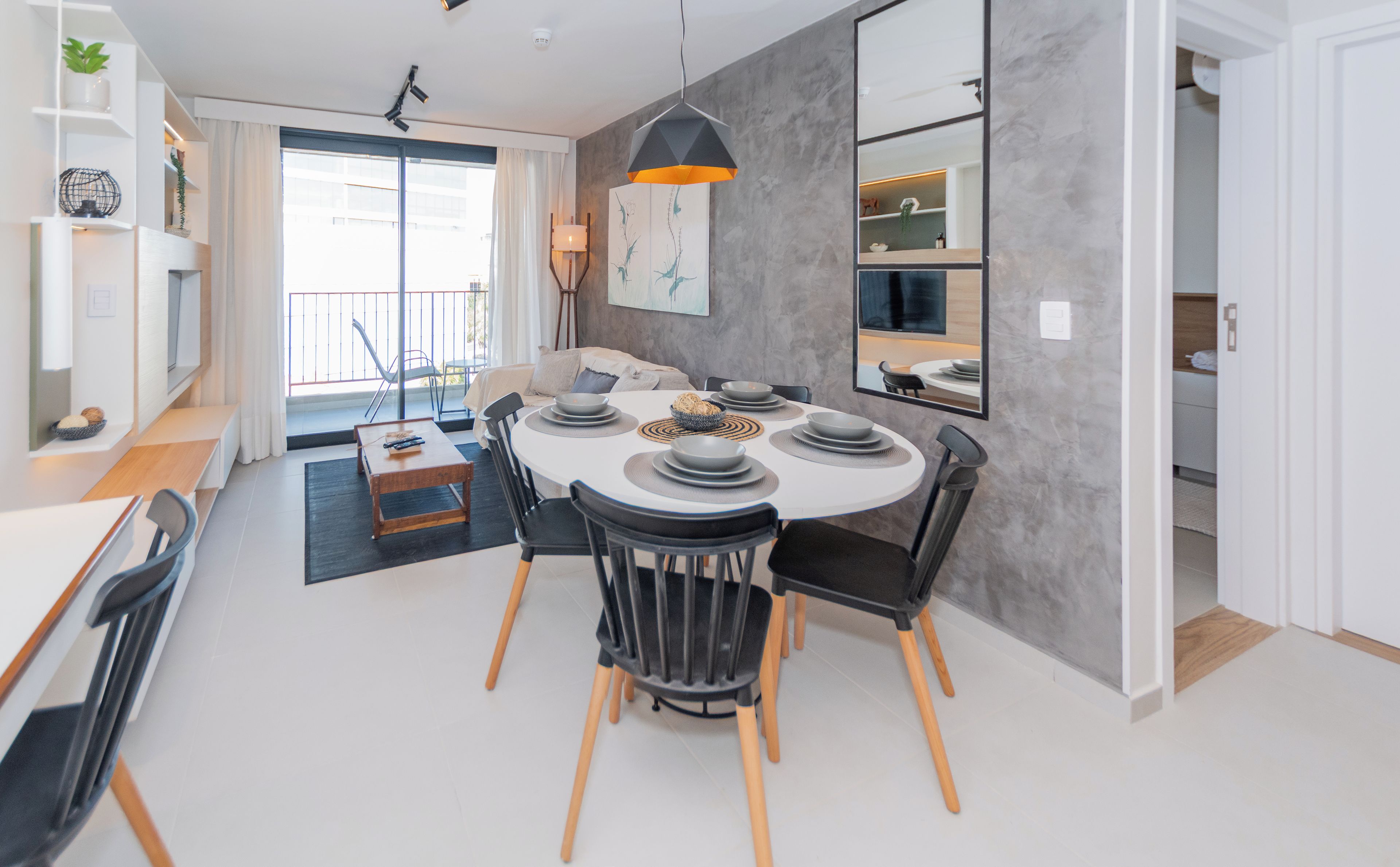 A modern dining area with a round table, black chairs, and a central light fixture.