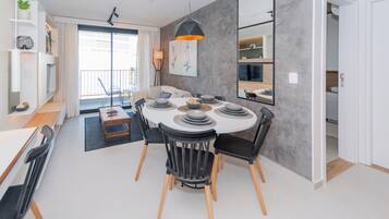 A modern dining area with a round table, black chairs, and a central light fixture.