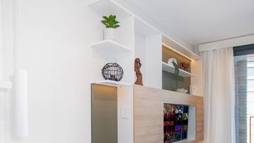 A modern living room with a built-in entertainment unit, a seating area, and a view of the outdoors.