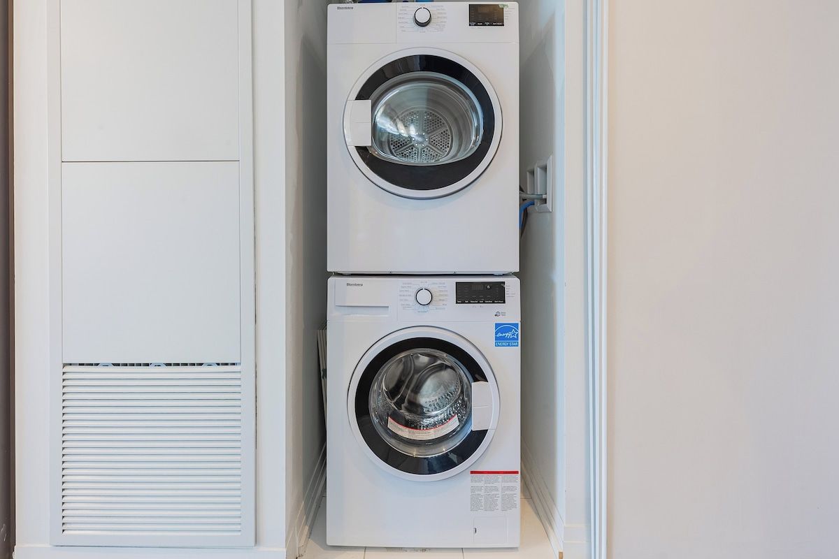 Two stacked front-loading washing machines in a laundry room.