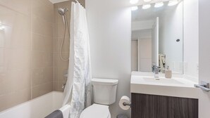 Et moderne badeværelse med badekar, toilet og vaskebord.