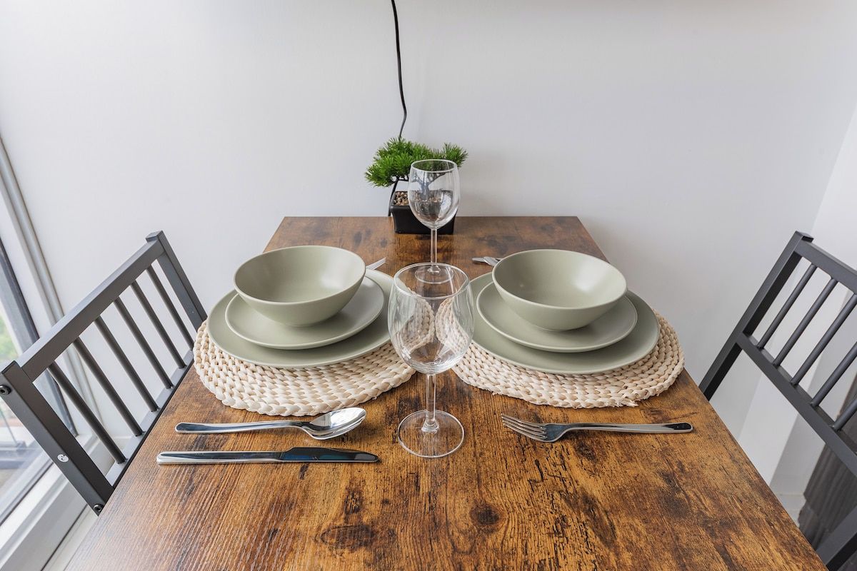 A dining table with a glass of water, two plates, and cutlery.
