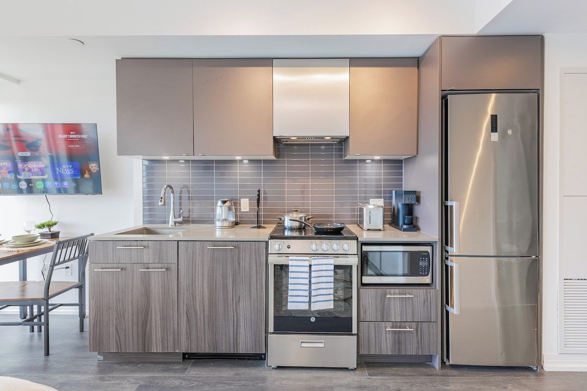 A modern kitchen with a stainless steel refrigerator, built-in oven, and a microwave.