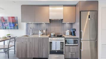 A modern kitchen with a stainless steel refrigerator, built-in oven, and a microwave.