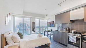 Et moderne hotelværelse med en stor seng, et tekøkken og udsigt over byen.