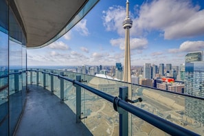 Een hoog gebouw met een glazen balkon met uitzicht op een stadsgezicht, inclusief een opvallende toren.