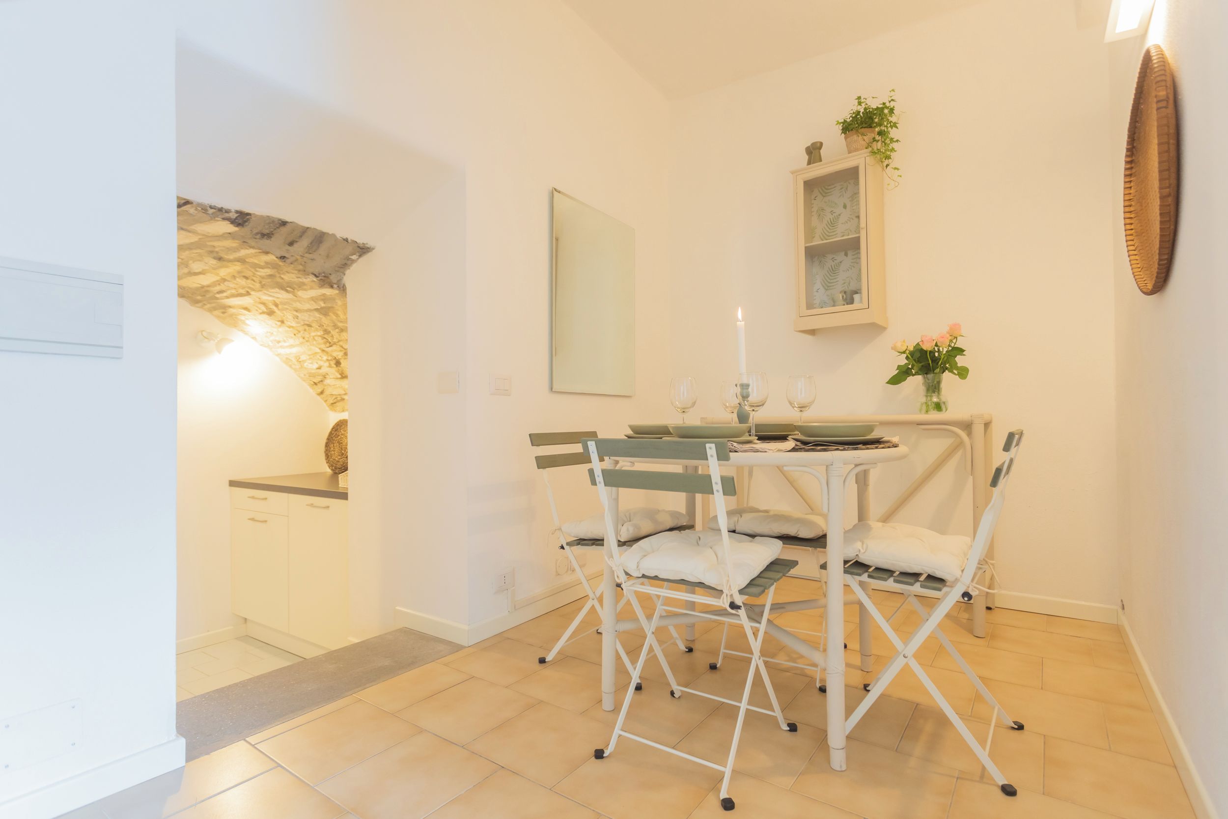 Een eethoek met een tafel, stoelen, een kaars en een spiegel aan de muur.