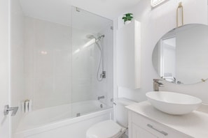 Ein modernes Badezimmer mit einer Duschkabine aus Glas, einem weißen Waschbecken und einem Spiegel darüber.