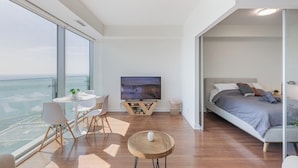 Een moderne slaapkamer met een bed, een televisie en een balkon met uitzicht.