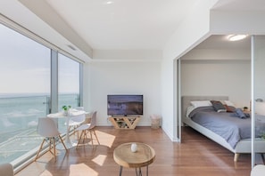 Ein modernes Schlafzimmer mit Bett, Fernseher und Balkon mit Blick.